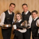 Vancouver's Singing Servers feature vocalists dressed in the same attire as the serving staff embedded with the other waiters. The singers would interact with the guests performing simple server duties to establish their characters. One of the servers would begin to hum a classic doo-wop song to himself. Another begins to clink glasses in a rhythmic manner…a third begins to snap her fingers. Suddenly another waiter begins to sing and a musical call & response takes place across the room as wonderment sweeps over the ballroom. Each of these musical elements come together as the Singing Servers move amongst the guests. The group breaks into a four part of a cappella sounds of Huey Lewis' "That's Alright' as they converge onto the stage. After brief introductions the ensemble performs their signature vocal arrangement of the epic Rock Song "Bohemian Rhapsody" by Queen. The show continues with a musical revue of Broadway and popular songs performed with the energy and excitement of the popular Television show "Glee". Vancouver's Singing Servers feature four of our city's top singer/entertainers each with vast musical theatre experience.